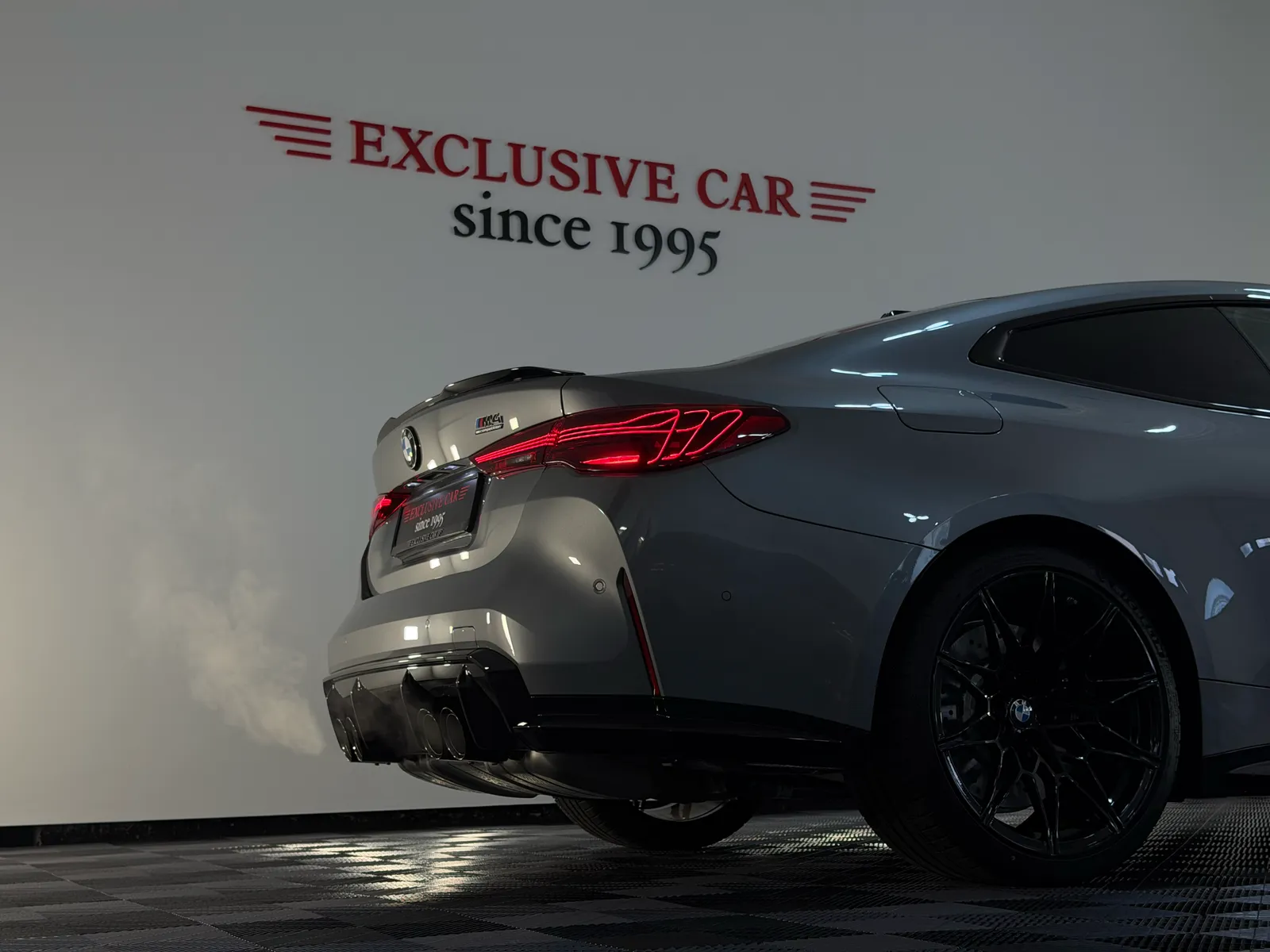 Zadní část šedého BMW M4 v showroomu Exclusive Car